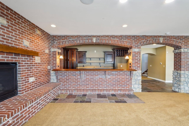 kitchen featuring brick wall and a kitchen bar