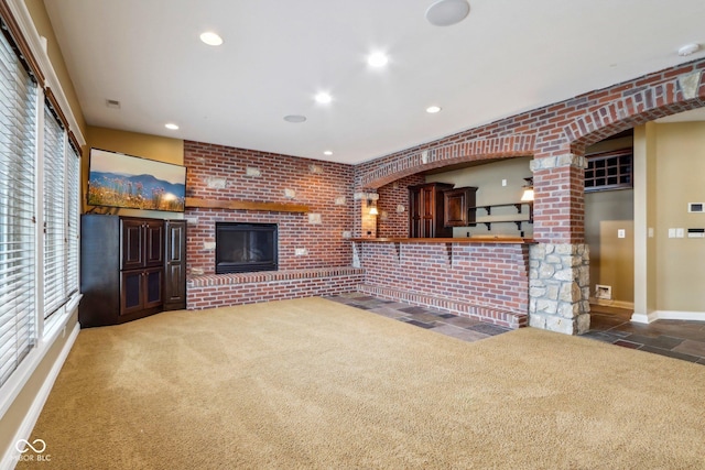 unfurnished living room featuring a brick fireplace and carpet