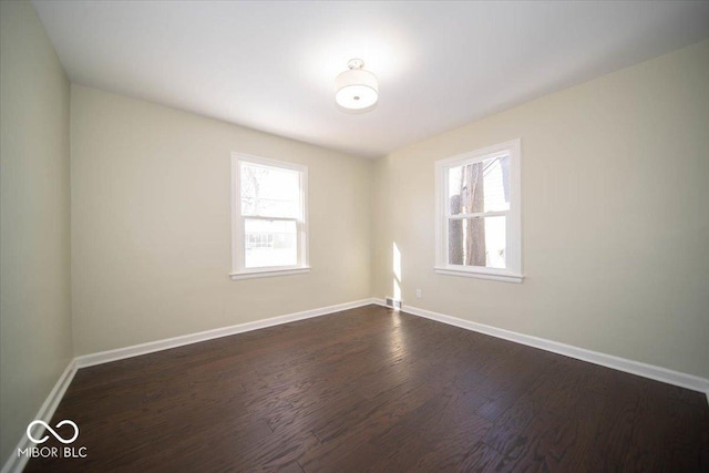 spare room featuring a healthy amount of sunlight and dark hardwood / wood-style flooring