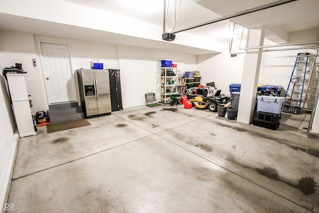 garage with a garage door opener and stainless steel refrigerator with ice dispenser