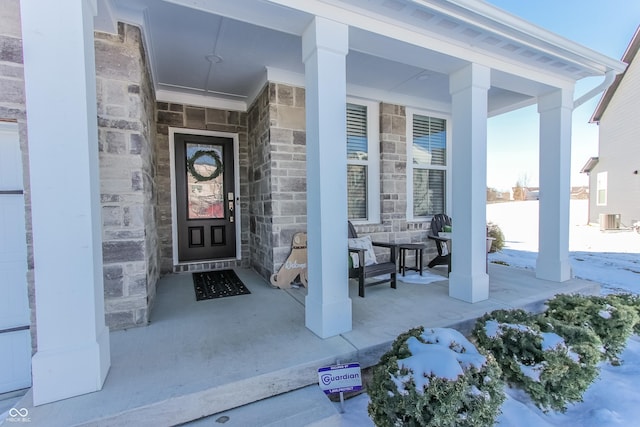 snow covered property entrance featuring central AC unit and covered porch