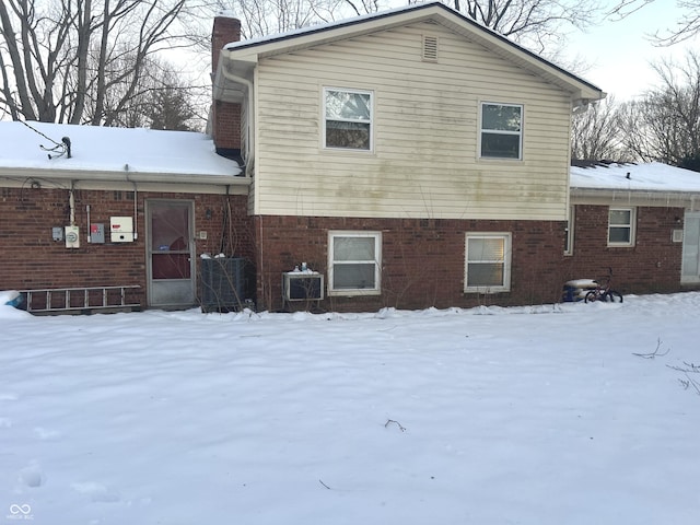 snow covered back of property with central AC