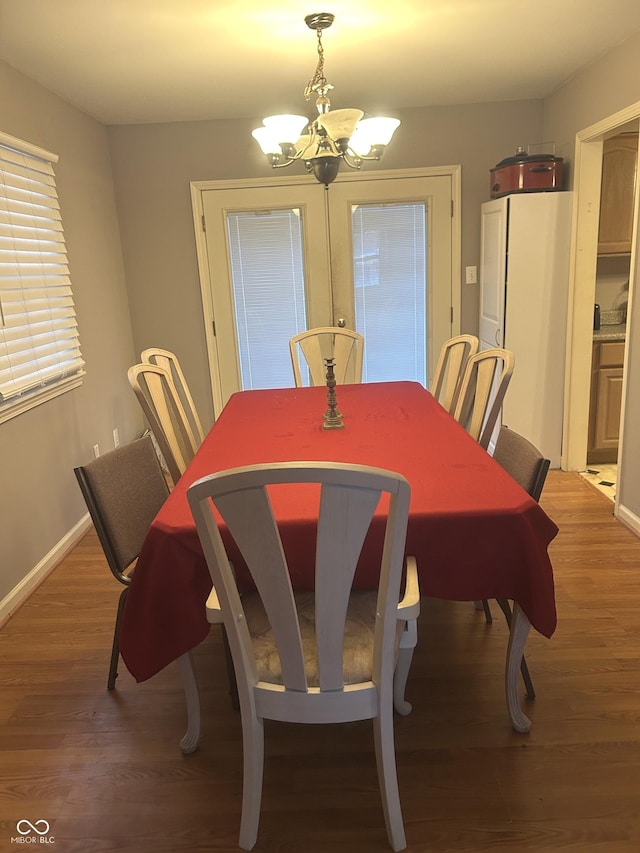 dining area with dark wood-type flooring and an inviting chandelier