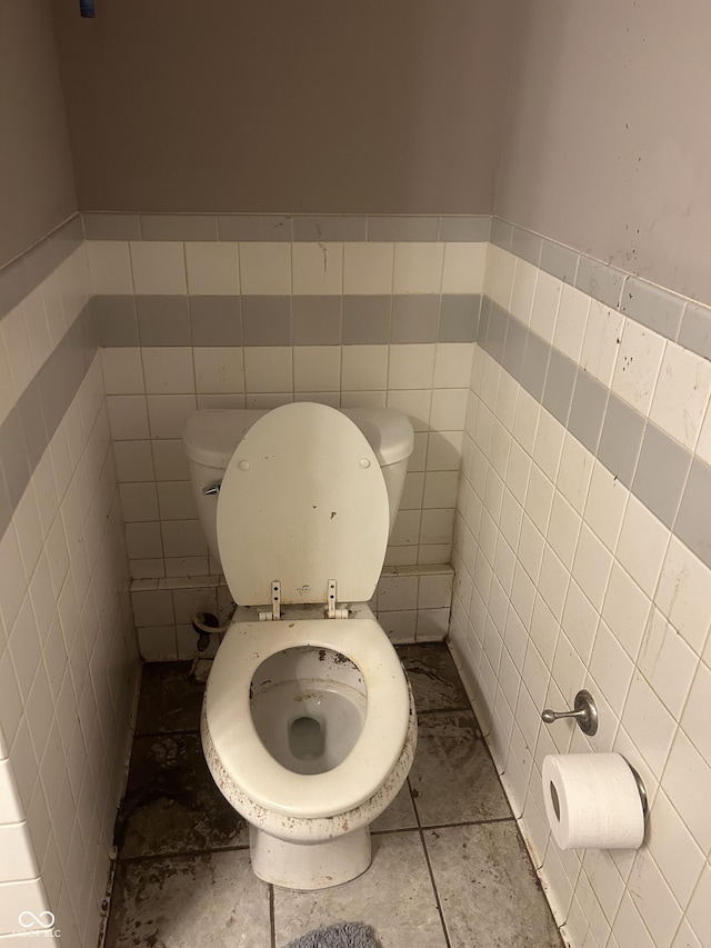 bathroom with toilet, tile walls, and tile patterned floors