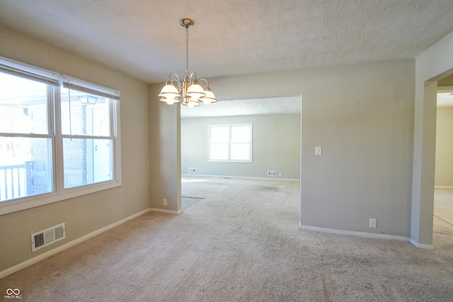 unfurnished room featuring an inviting chandelier and light carpet