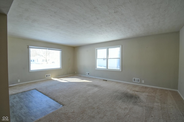 empty room featuring a textured ceiling and light colored carpet