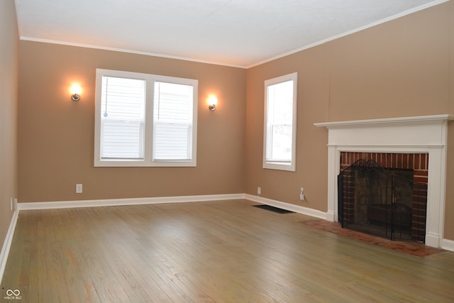 unfurnished living room featuring a brick fireplace, ornamental molding, and hardwood / wood-style flooring