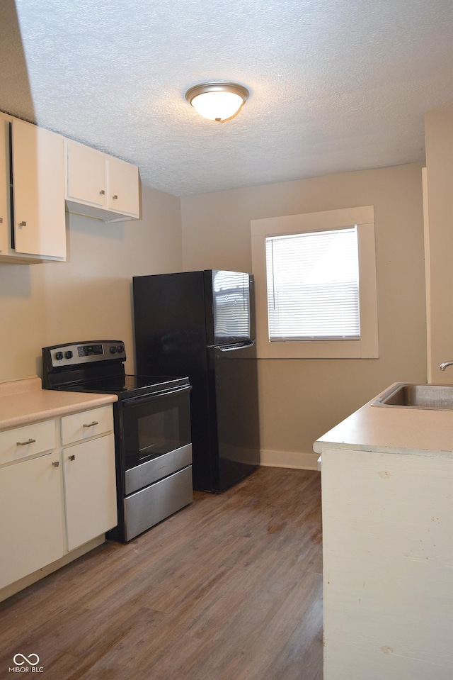 kitchen with white cabinets, black refrigerator, light wood-type flooring, stainless steel electric range, and sink