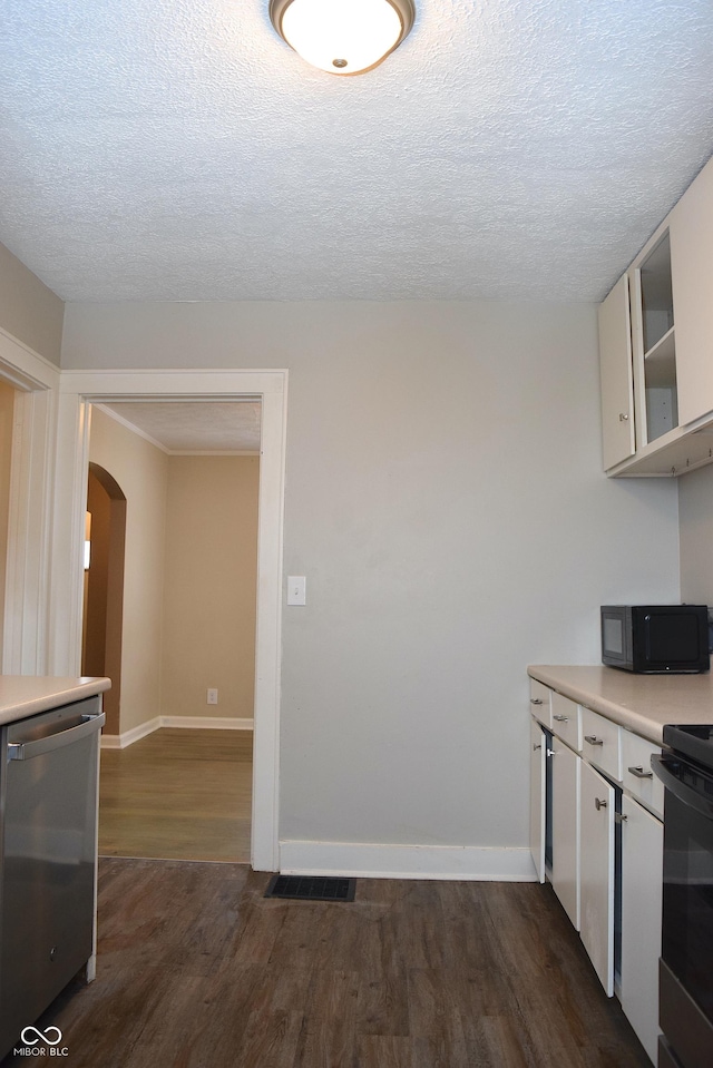 kitchen featuring stainless steel appliances, a textured ceiling, white cabinets, and dark hardwood / wood-style flooring