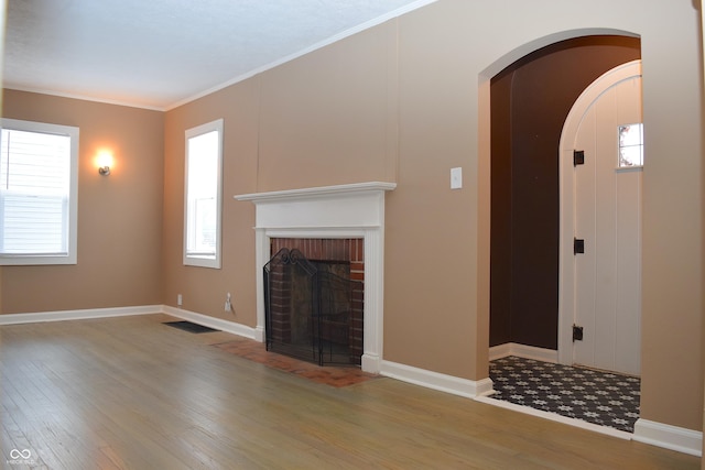 unfurnished living room with a brick fireplace, crown molding, and hardwood / wood-style flooring