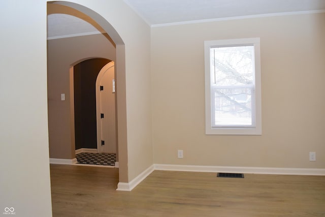 empty room featuring a healthy amount of sunlight, crown molding, and light hardwood / wood-style flooring