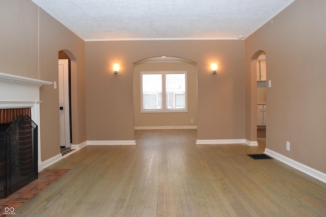 unfurnished living room with a fireplace, light hardwood / wood-style floors, and crown molding