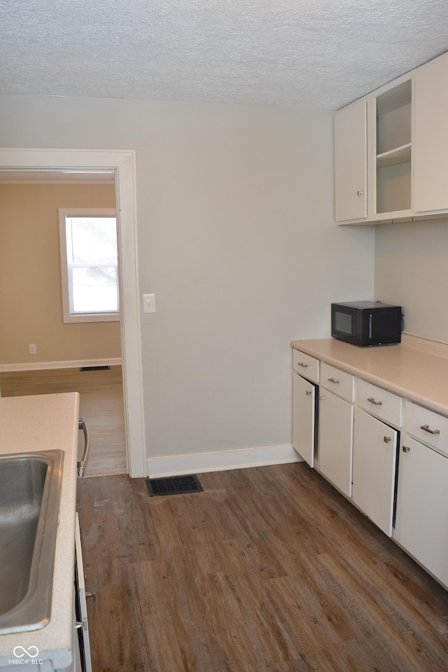 kitchen featuring white cabinets, dark hardwood / wood-style flooring, sink, and a textured ceiling