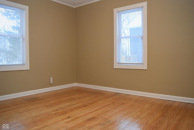 spare room with a wealth of natural light, light hardwood / wood-style flooring, and crown molding