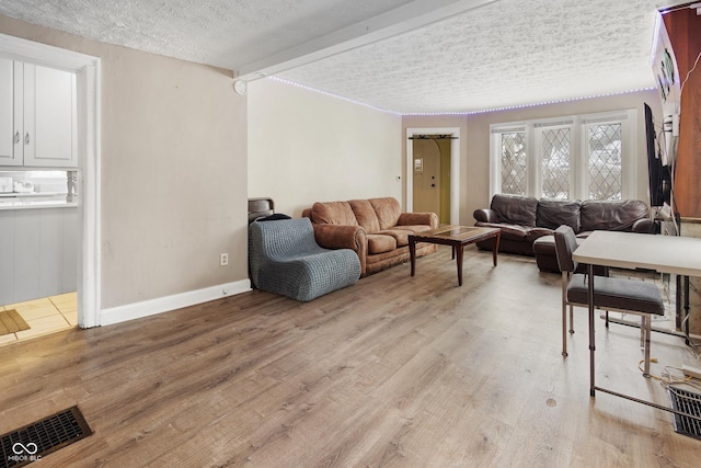 living room with beamed ceiling, a textured ceiling, and light wood-type flooring