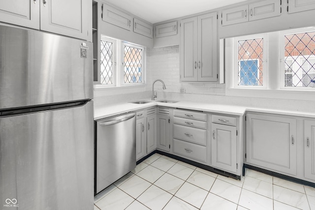 kitchen with gray cabinetry, sink, light tile patterned floors, and appliances with stainless steel finishes