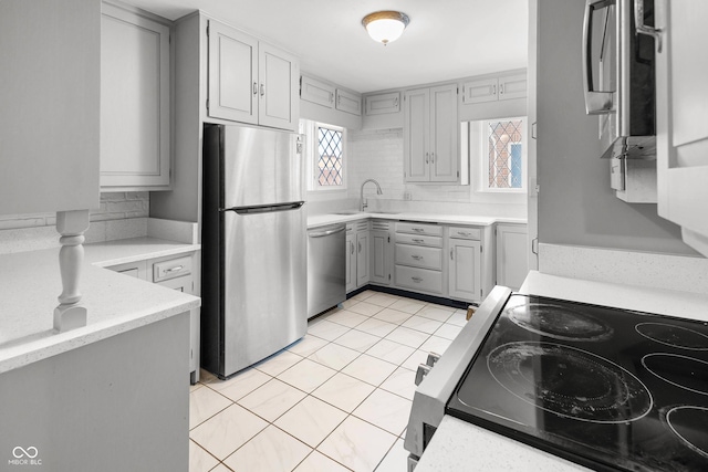 kitchen with gray cabinets, sink, light tile patterned floors, and appliances with stainless steel finishes