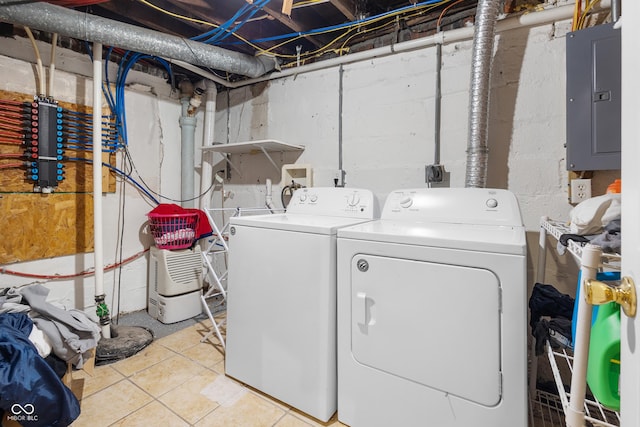 clothes washing area featuring washing machine and dryer, light tile patterned floors, and electric panel