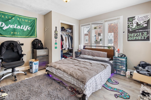 bedroom with stainless steel fridge, a closet, a textured ceiling, and light hardwood / wood-style flooring