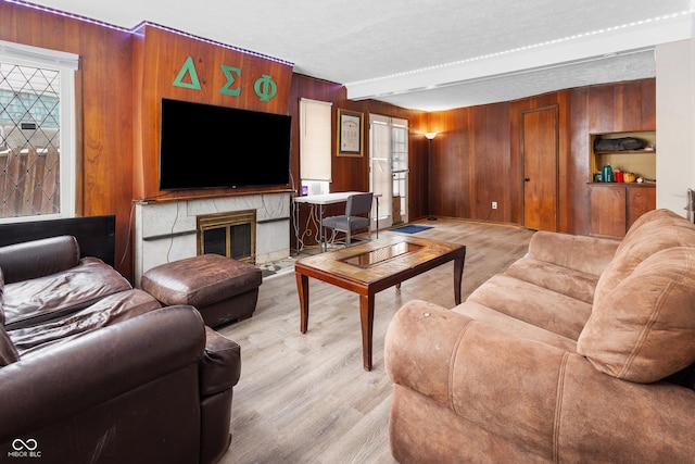 living room featuring wood walls, beamed ceiling, a textured ceiling, and light wood-type flooring