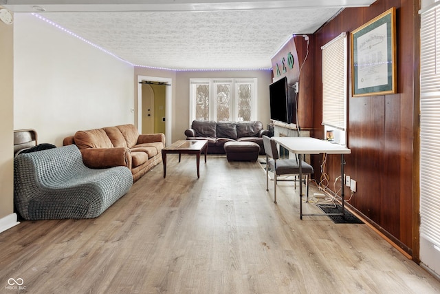 living room featuring light hardwood / wood-style floors, a textured ceiling, and wooden walls