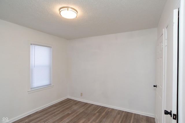 spare room featuring a textured ceiling and dark wood-type flooring