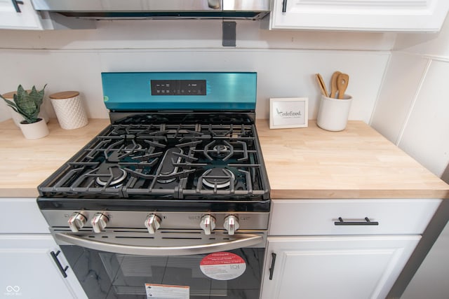 room details featuring white cabinetry, stainless steel gas stove, and wooden counters