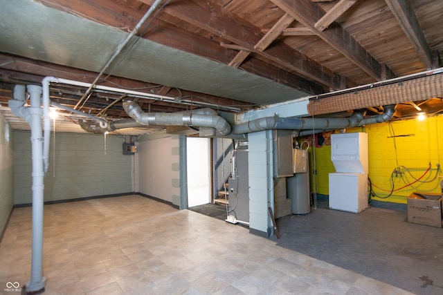 basement featuring gas water heater and stacked washer / dryer