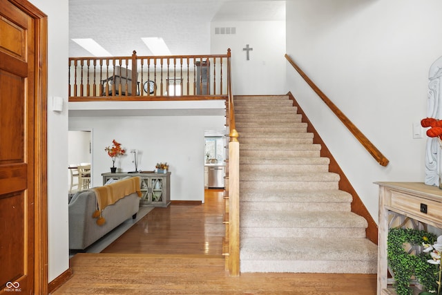 stairway with a skylight and hardwood / wood-style floors