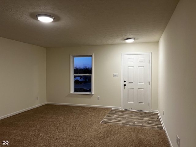 interior space featuring baseboards, dark colored carpet, and a textured ceiling