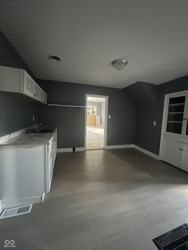 kitchen with white cabinets, vaulted ceiling, and sink