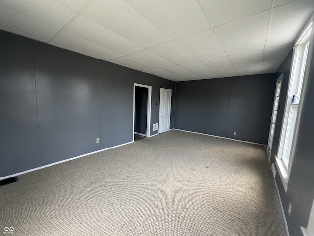 carpeted empty room featuring a drop ceiling