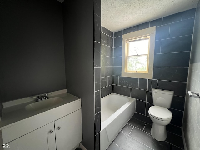 bathroom featuring vanity, toilet, a textured ceiling, and tile walls