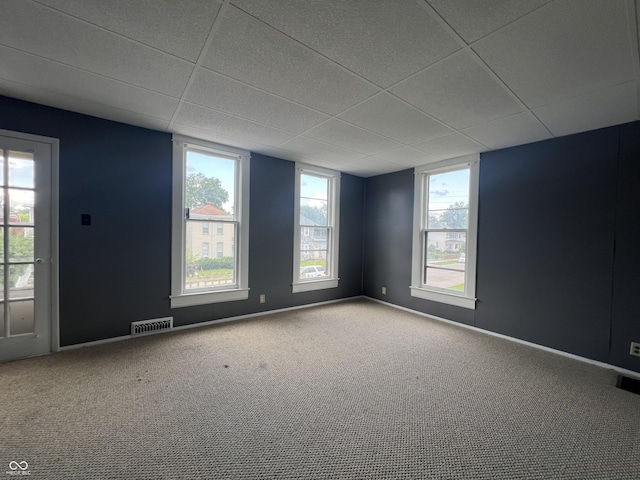 carpeted empty room featuring a paneled ceiling