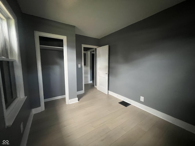 unfurnished bedroom with light wood-type flooring and a closet