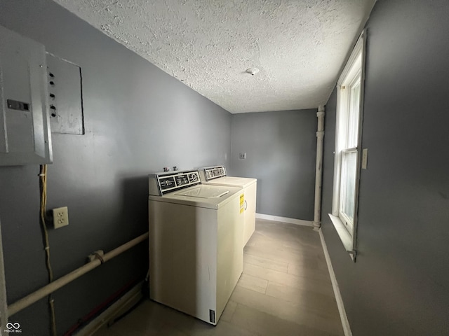 clothes washing area featuring electric panel, washer and clothes dryer, a textured ceiling, and hardwood / wood-style flooring