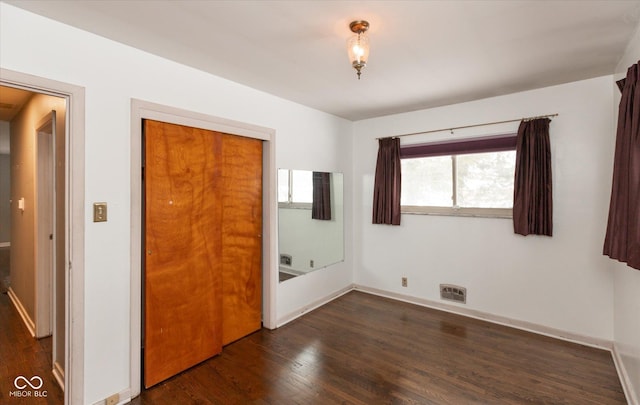 unfurnished bedroom featuring dark hardwood / wood-style flooring and a closet