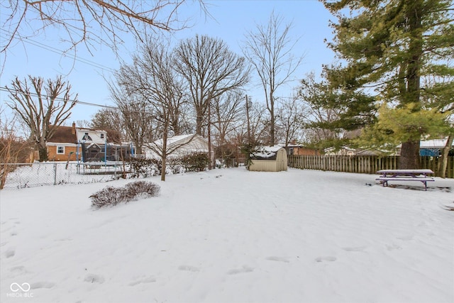 yard layered in snow with a trampoline