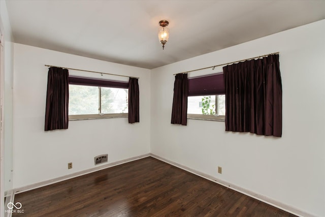 empty room featuring dark wood-type flooring and plenty of natural light