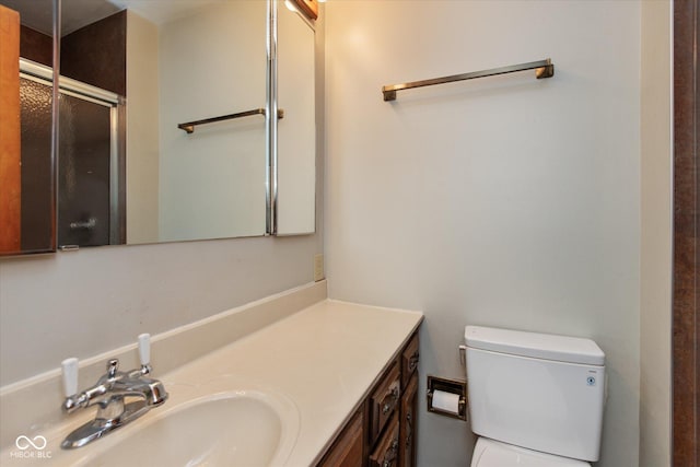 bathroom featuring vanity, a shower with shower door, and toilet