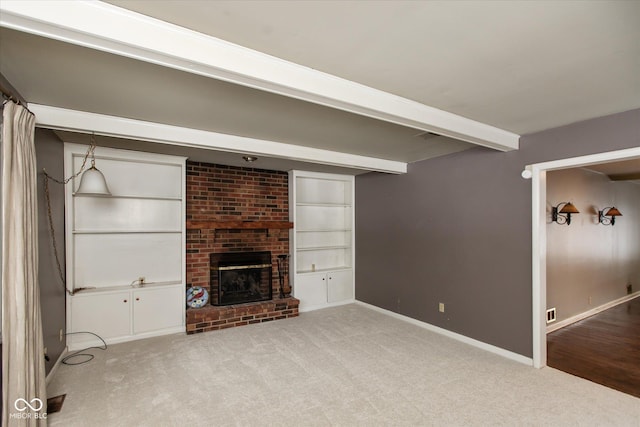 unfurnished living room with beamed ceiling, light carpet, a fireplace, and built in shelves