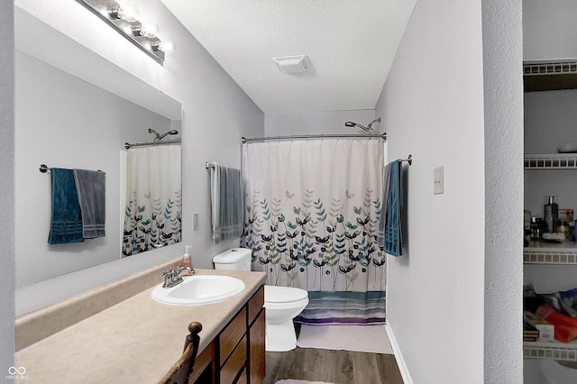 bathroom featuring toilet, a textured ceiling, wood-type flooring, and vanity