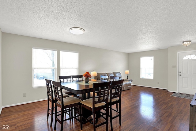 dining area with dark wood-type flooring and a textured ceiling