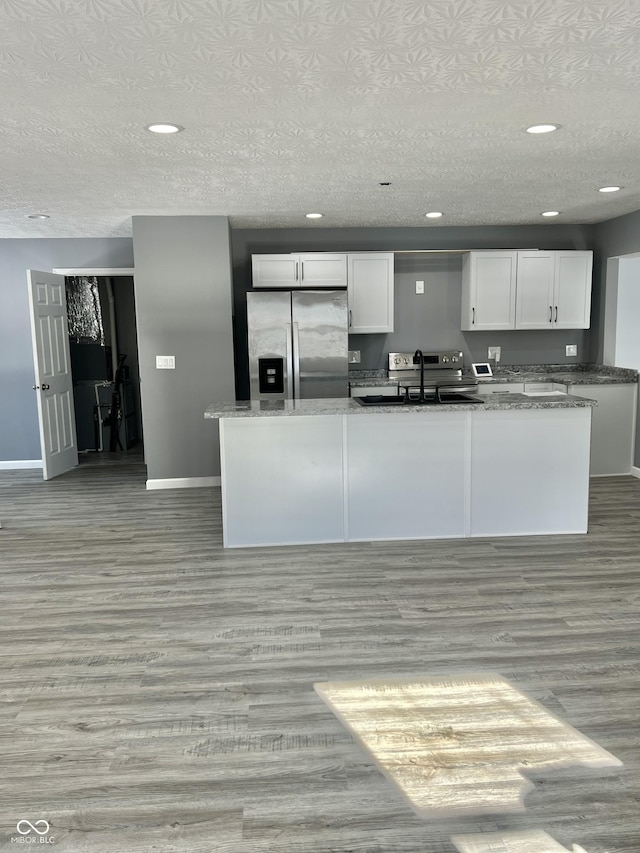 kitchen featuring dark stone countertops, stainless steel fridge with ice dispenser, sink, light hardwood / wood-style flooring, and white cabinetry