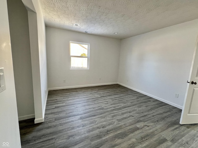 spare room featuring a textured ceiling and dark hardwood / wood-style floors