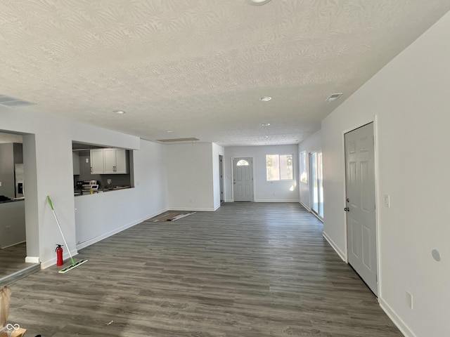 unfurnished living room with a textured ceiling and dark wood-type flooring