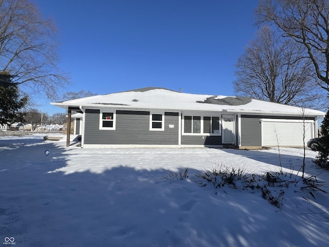 snow covered back of property with a garage