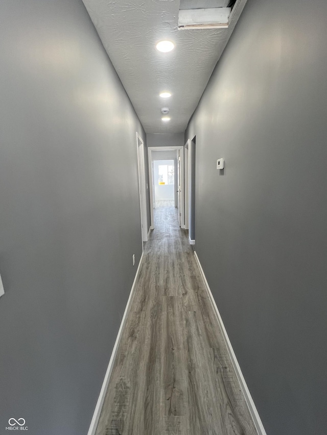 corridor featuring a textured ceiling and wood-type flooring