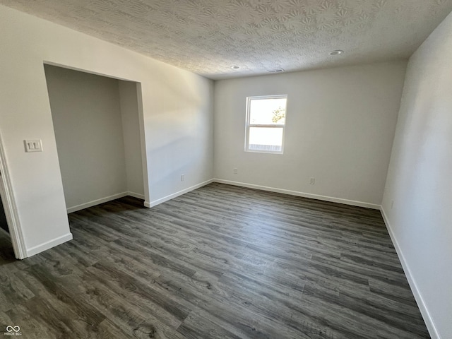 unfurnished room featuring a textured ceiling and dark wood-type flooring