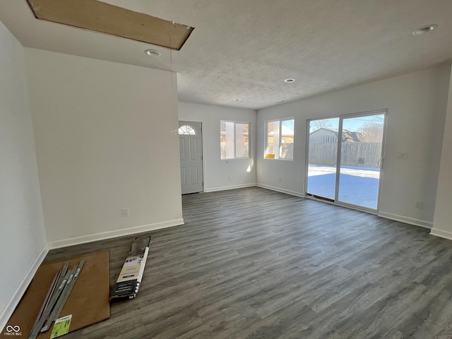 unfurnished living room with a textured ceiling and dark hardwood / wood-style floors